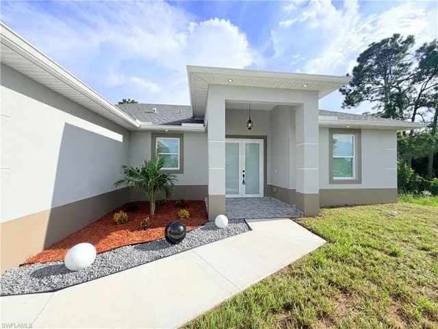 Modern exterior with a covered entry, double entry doors, paved front porch, and a landscaped garden bed featuring gravel and mulch