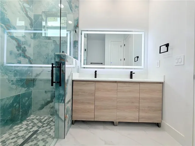 Glass-enclosed shower with teal-toned wall tiles and mosaic floor tiles