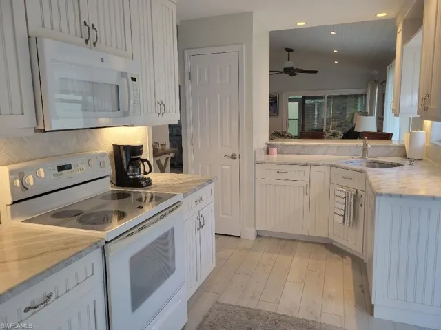 Kitchen featuring white appliances, light wood-style flooring, recessed lighting, white cabinetry, and decorative backsplash