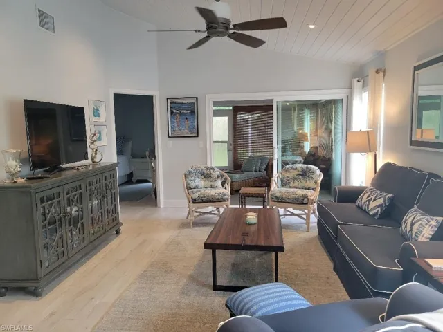 Living room with healthy amount of natural light, vaulted ceiling, light wood-style flooring, wooden ceiling, and a ceiling fan