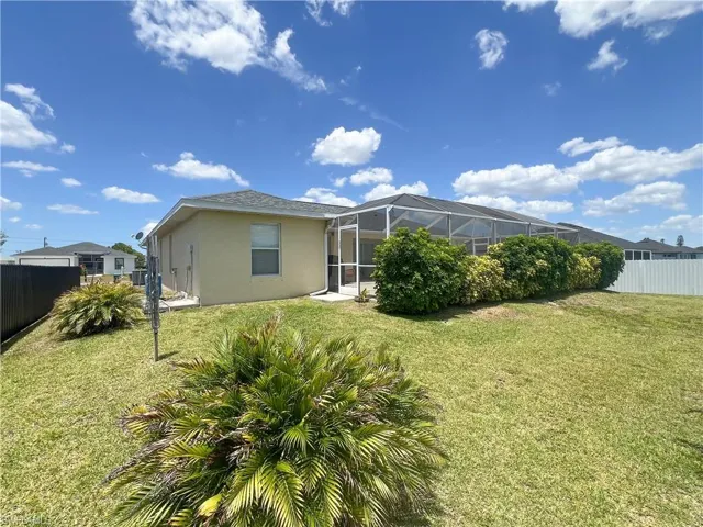 Back of property with stucco siding, a lanai, fence, and a yard