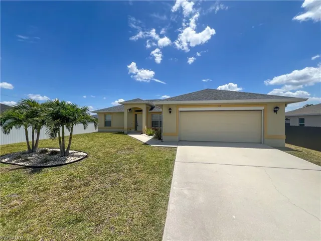 View of front facade featuring an attached garage, driveway, a front lawn, and stucco siding