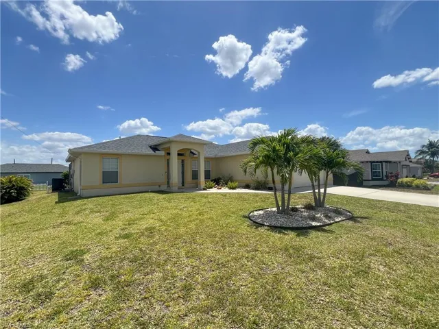 View of front facade featuring an attached garage, driveway, a front yard, and stucco siding
