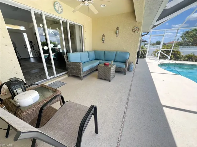 View of patio with an outdoor hangout area, glass enclosure, ceiling fan, and an outdoor pool