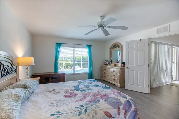Bedroom with a ceiling fan, wood finished floors, and visible vents