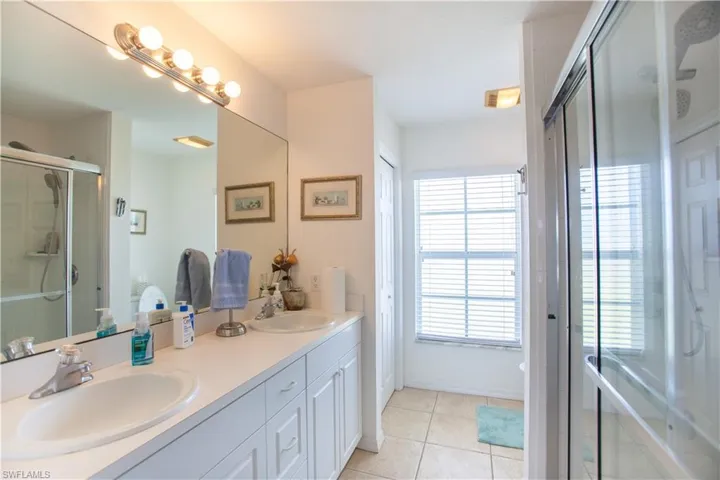 Full bath with double vanity, a sink, plenty of natural light, and a stall shower