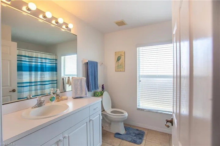 Full bath with tile patterned flooring, vanity, toilet, curtained shower, and visible vents