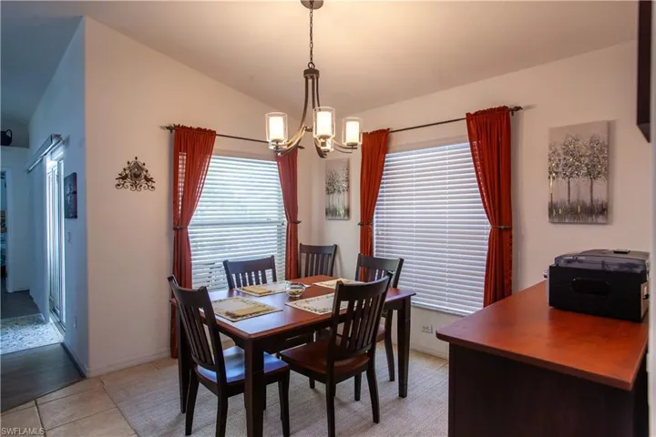 Dining space with light tile patterned floors, lofted ceiling, and a chandelier