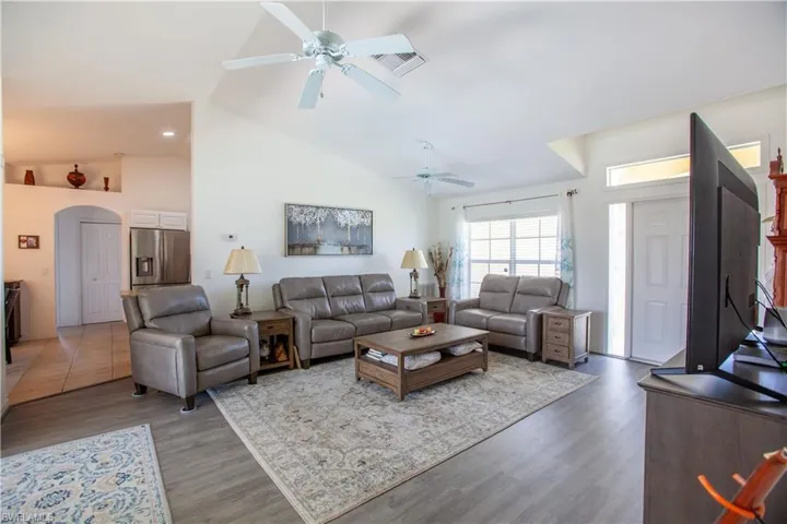 Living room with visible vents, ceiling fan, wood finished floors, and high vaulted ceiling