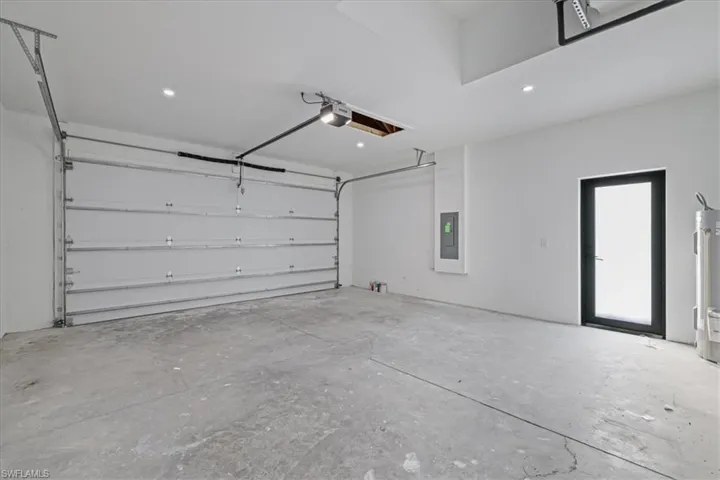 Garage featuring water heater, recessed lighting, and a garage door opener