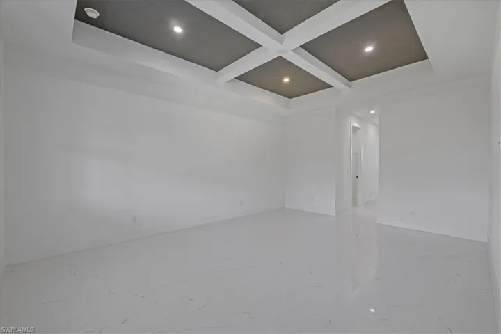 Unfurnished room with coffered ceiling, light marble finish floors, and recessed lighting