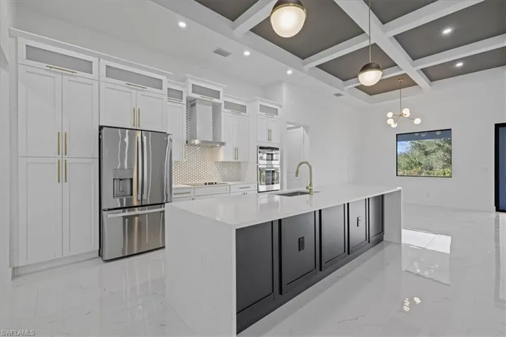 Kitchen featuring stainless steel appliances, coffered ceiling, glass fronted cabinets, light stone countertops, and light marble finish flooring