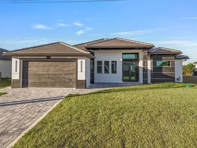 View of front of property with stucco siding, a front yard, decorative driveway, and french doors