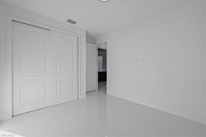 Unfurnished bedroom featuring a closet and light marble finish flooring