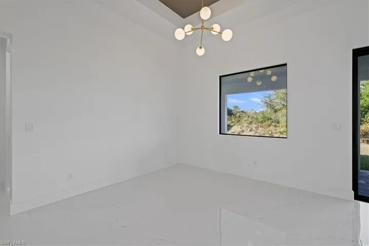 Unfurnished dining area featuring a chandelier and light marble finish flooring