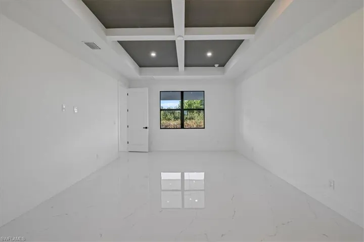 Unfurnished room with coffered ceiling, recessed lighting, and light marble finish flooring