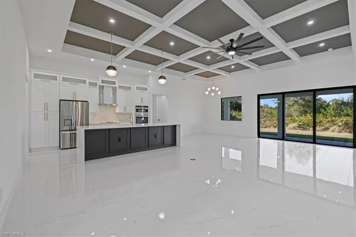 Kitchen with glass fronted cabinets, open floor plan, stainless steel appliances, a spacious island, and dual tone cabinetry