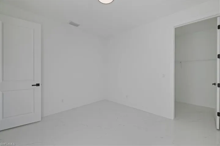 Unfurnished bedroom featuring a spacious closet and light marble finish floors