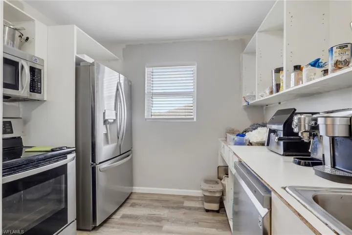 Kitchen featuring open shelves, stainless steel appliances, light countertops, and white cabinetry