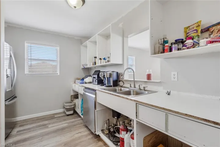 Kitchen with open shelves, light countertops, white cabinetry, light wood-style floors, and stainless steel appliances
