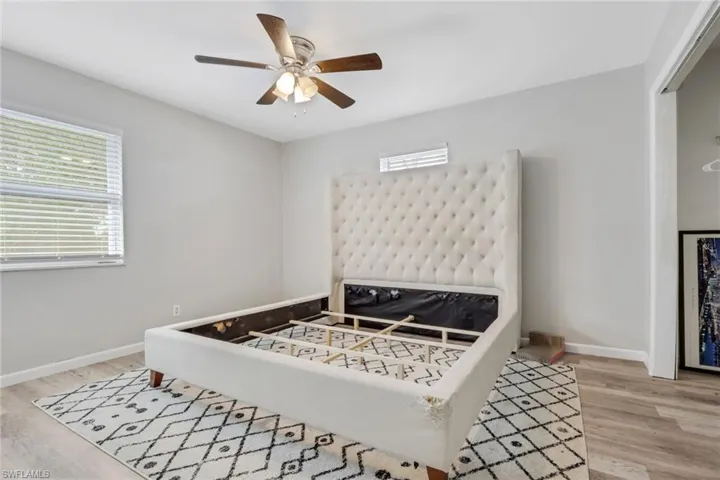 Bedroom with light wood finished floors, multiple windows, and ceiling fan