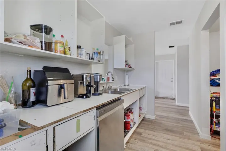 Kitchen featuring open shelves, light countertops, white cabinets, dishwasher, and light wood-type flooring