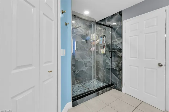 Bathroom with a marble finish shower, a closet, and recessed lighting