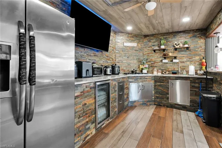 Bar area with stainless steel fridge, light wood-type flooring, beverage cooler, recessed lighting, and a ceiling fan