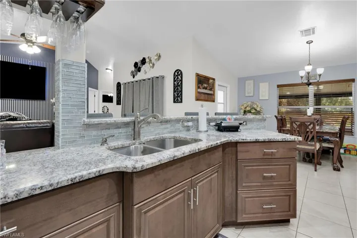 Kitchen featuring light stone countertops, light tile patterned floors, ceiling fan, lofted ceiling, and decorative light fixtures