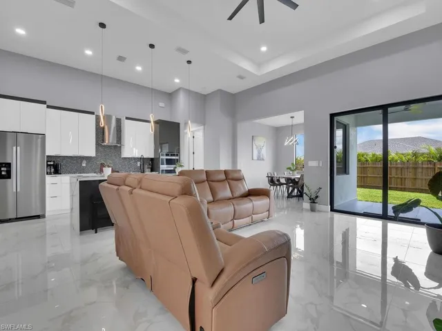 Tiled living room featuring a raised ceiling, ceiling fan, a high ceiling, and sink