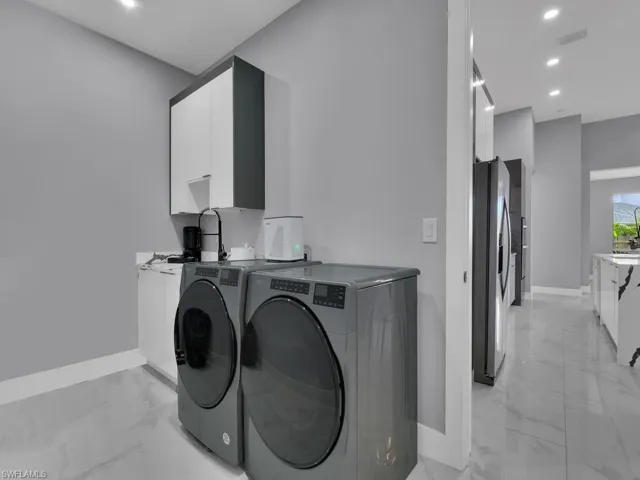 Washroom featuring washer and dryer and light tile floors