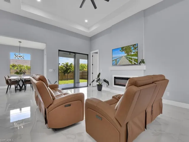 Living room featuring a towering ceiling, a tray ceiling, and light tile flooring
