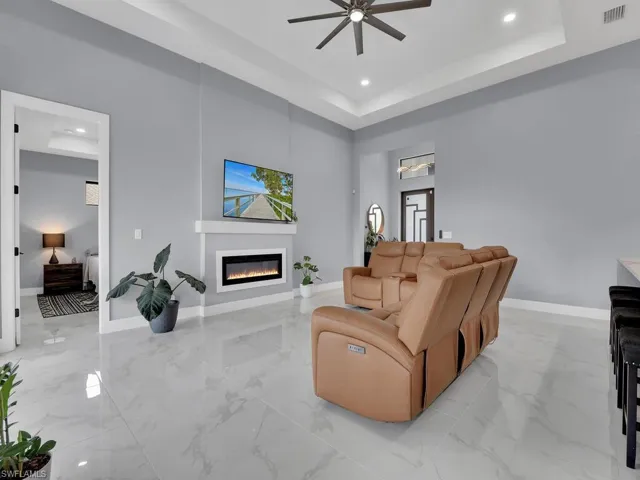 Tiled living room with a towering ceiling, ceiling fan, and a raised ceiling