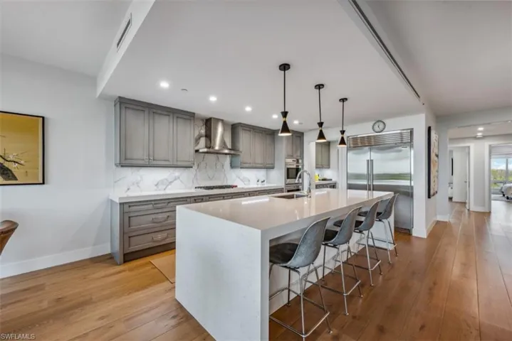 Kitchen with gray cabinetry, a breakfast bar area, pendant lighting, appliances with stainless steel finishes, and recessed lighting