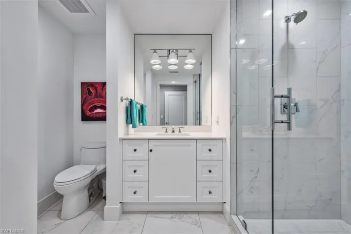 Bathroom with a marble finish shower, vanity, and light marble finish floors