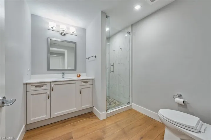 Bathroom featuring vanity, a marble finish shower, and light wood-style flooring