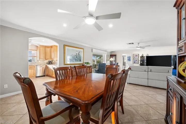 Dining room with a ceiling fan, plenty of natural light, ornamental molding, recessed lighting, and arched walkways.
