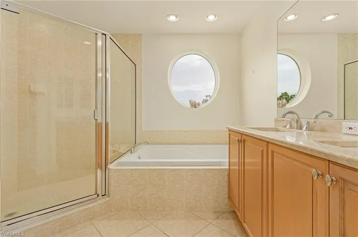 Bathroom with tile patterned flooring, vanity, and plus walk in shower
