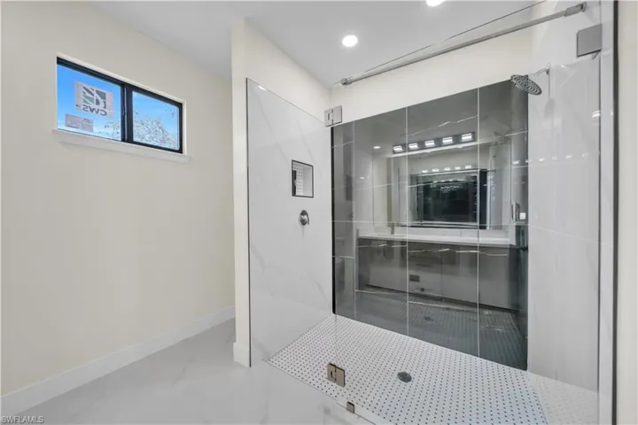 Glass-enclosed shower featuring a rainfall showerhead, recessed shower niche, and a tiled shower pan