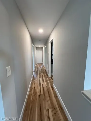 Hall with baseboards and wood finished floors