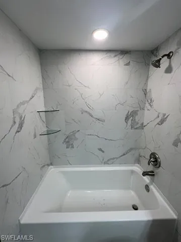 Bathroom featuring a combined bath / shower with marble appearance