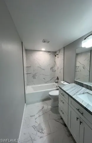 Bathroom featuring light marble finish floors, vanity, and a combined bath / shower with marble appearance