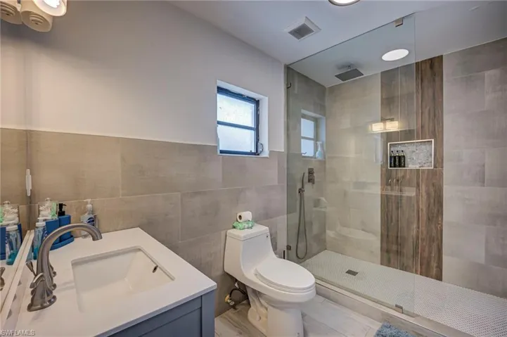 Full bath with vanity, walk in shower, and tile walls