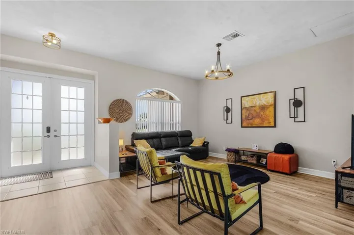 Living room featuring french doors, light wood finished floors, and a chandelier