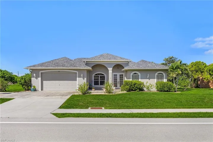 Ranch-style home with stucco siding, a front yard, concrete driveway, and an attached garage