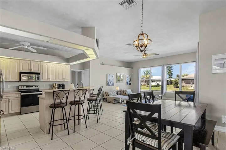 Kitchen featuring a ceiling fan, appliances with stainless steel finishes, light tile patterned flooring, a chandelier, and open floor plan
