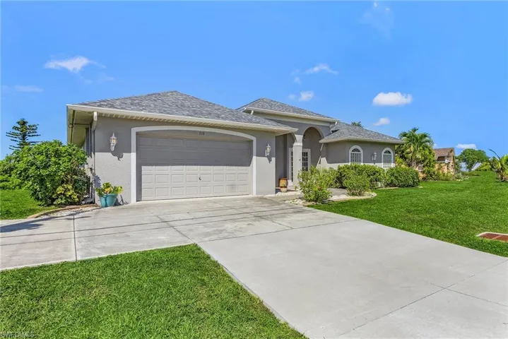 Ranch-style home featuring a garage, stucco siding, roof with shingles, driveway, and a front yard