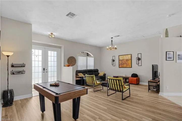 Game room featuring healthy amount of natural light, french doors, light wood-type flooring, and a chandelier