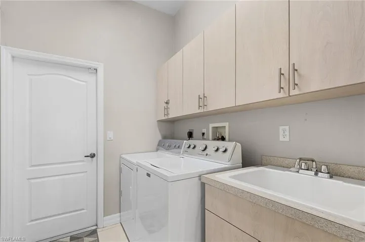 Laundry area featuring independent washer and dryer, cabinet space, and light tile patterned floors
