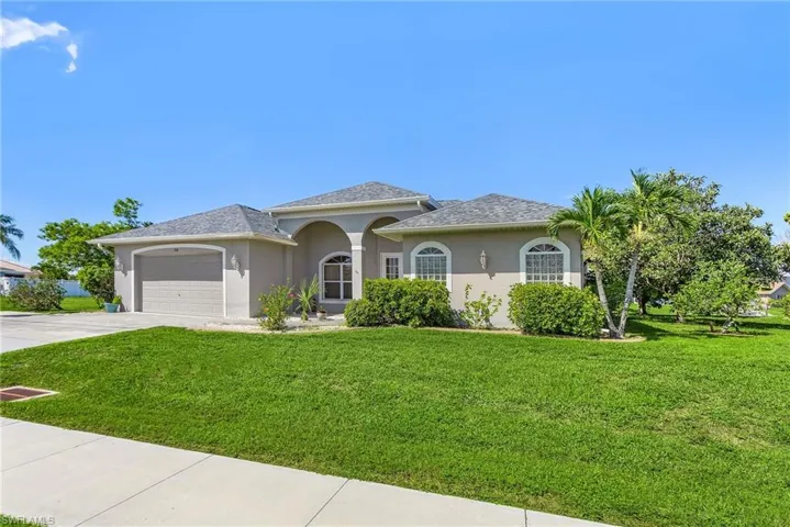 View of front of property with stucco siding, an attached garage, a front yard, and concrete driveway